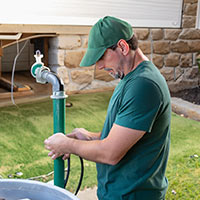 technician wearing green conducting a well inspection